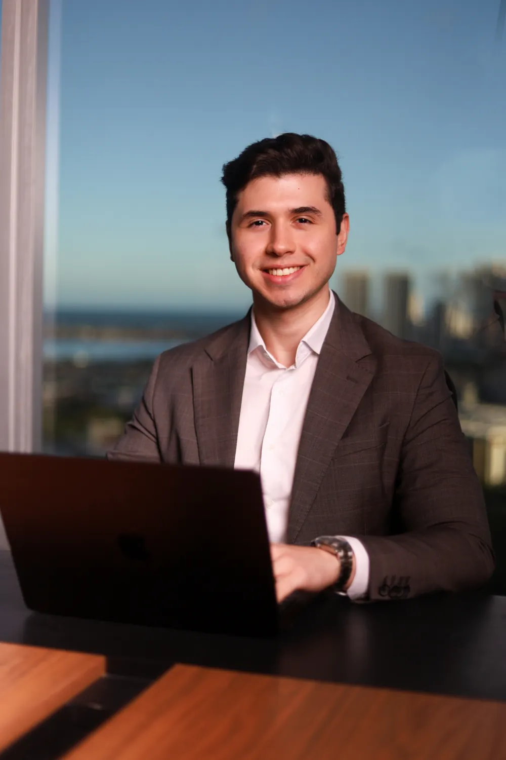 Leonardo França trabalhando no notebook, sorrindo, em seu escritório